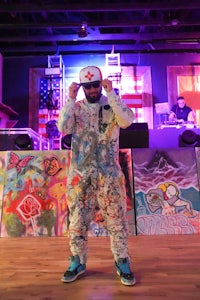 a man in a colorful jumpsuit standing in front of a stage